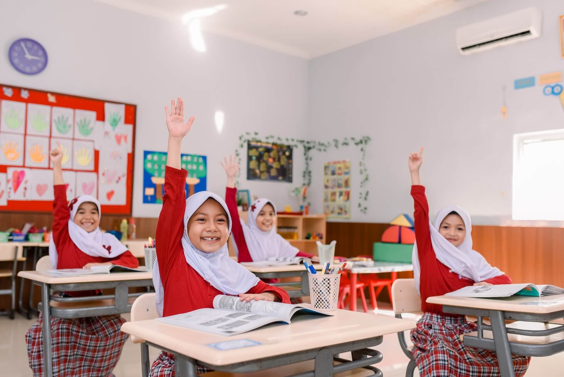 Prestige elementary students eagerly raising their hands during a lesson